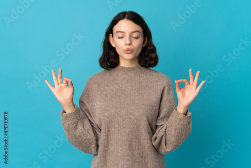 Teenager Ukrainian girl isolated on blue background in zen pose
