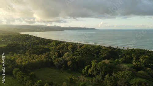 Aerial shot of a beautiful long beach in costa rica. Sunny day close to the pacific ocean and the tropical forest photo