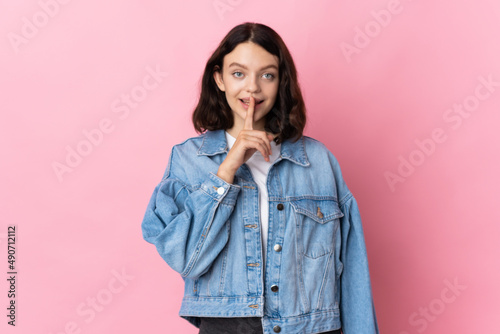 Teenager Ukrainian girl isolated on pink background showing a sign of silence gesture putting finger in mouth