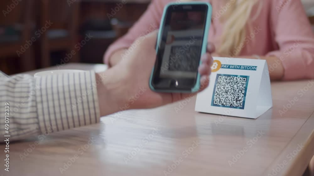 Cropped shot of man scan qr-code with smartphone in restaurant to pay. Realtime