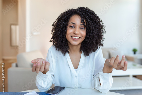 Photos African-american elegant female entrepreneur discussing while having a conference call Portrait of confident ethnicity female employee looking at camera talking on video call in the home office