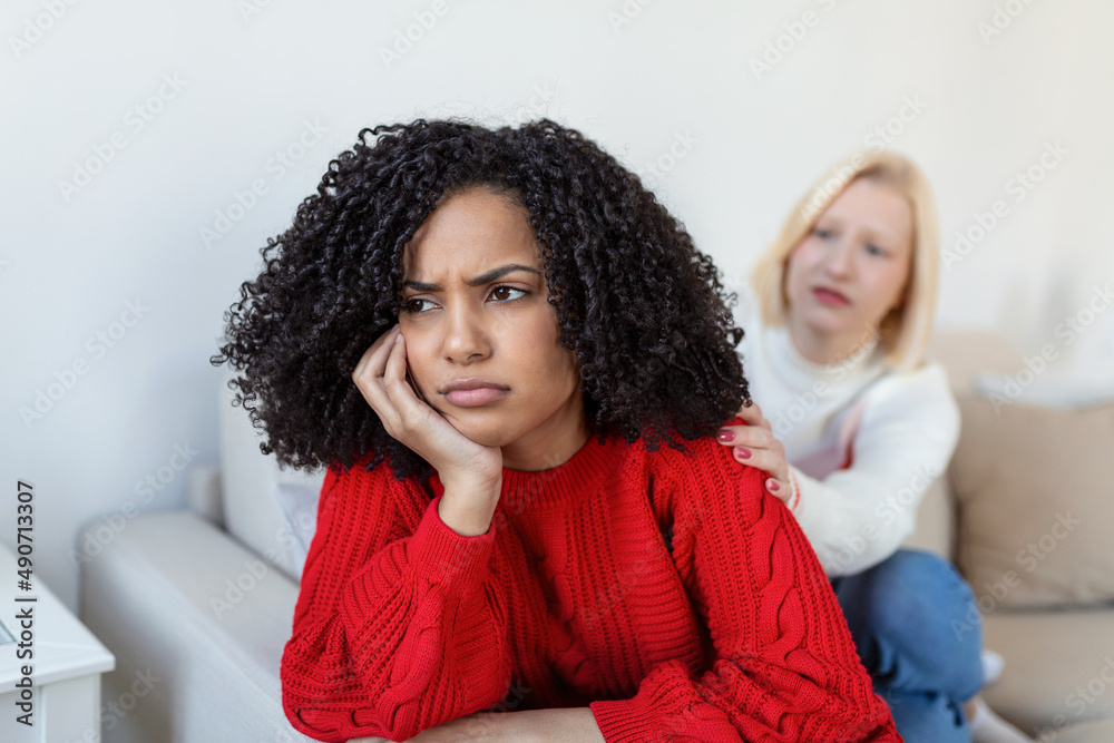 Two female friends sitting on sofa and arguing with each other. Friendship, quarrel, female disagreement, copy space. Angry couple or roommates sitting on a sofa in the living room at home Two female friends sitting on sofa and arguing with each other. Friendship, quarrel, female disagreement, copy space. Angry couple or roommates sitting on a sofa in the living room at home