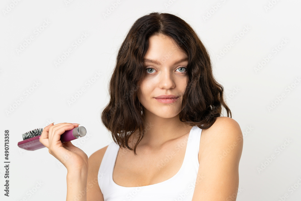 Teenager Ukrainian girl isolated on white background with hair comb Teenager Ukrainian girl isolated on white background with hair comb
