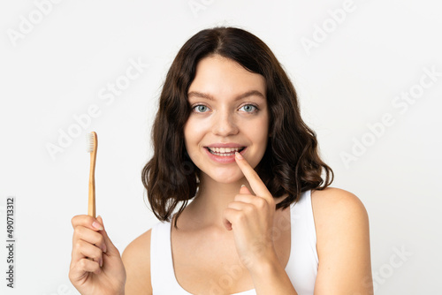 Teenager Ukrainian girl isolated on white background with a toothbrush and happy expression