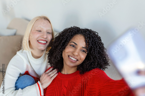 Shot of a two female friends taking selfie in the apartment. My roomies. Shot of two young women taking a selfie while sitting at home. Shared Living: roommates make a selfie