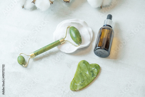 jade roller for facial massage gouache scraper brown bubble with serum , the concept of facial massage and home facial skin care