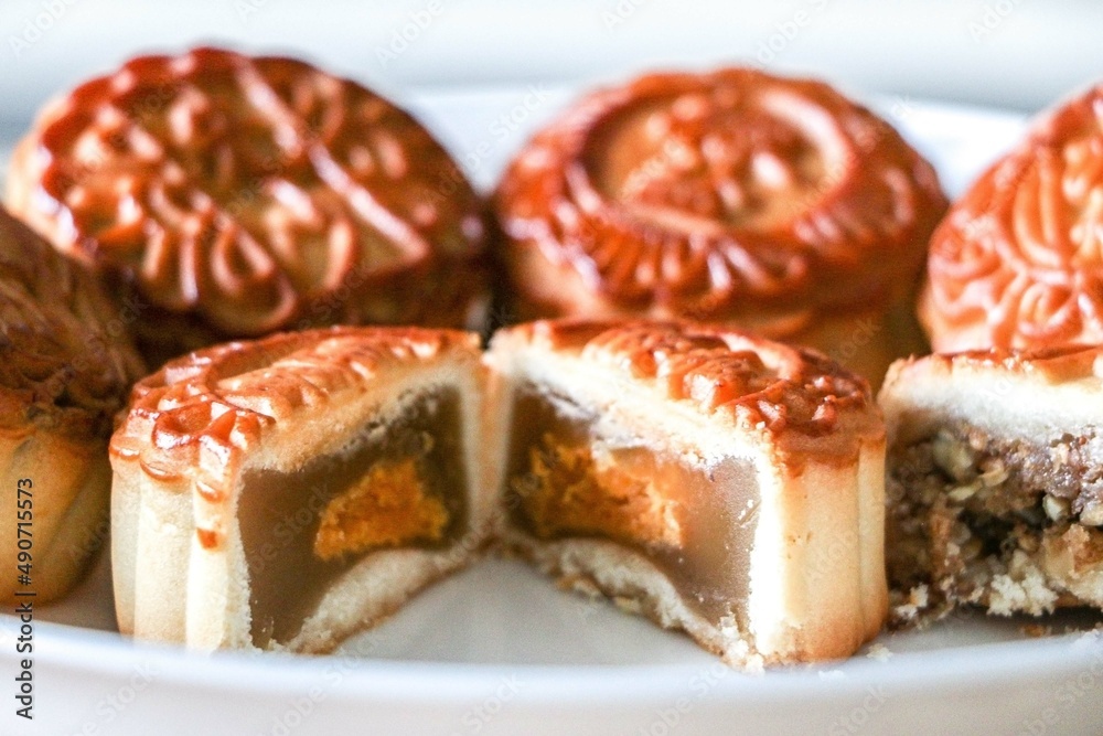 Mooncake cut in half showing traditional filling of lotus seed paste and egg yolk, egg yolk representing the moon for the Mid-Autumn (Mooncake) Festival, surrounded by other mooncake