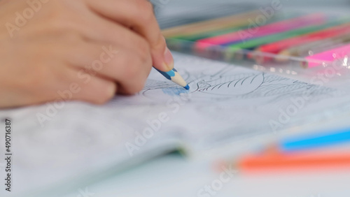 Drawing with pencil at home an Adult coloring book. hand holding a pencil and coloring an adult coloring book. person is coloring an illustrative
