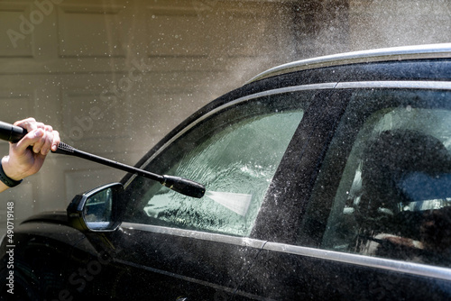 Selective focus shot of washing a black Suv 4wd car with high pressure washer cleaner. Car wash