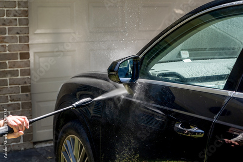 Selective focus shot of washing a black Suv 4wd car with high pressure washer cleaner. Car wash photo