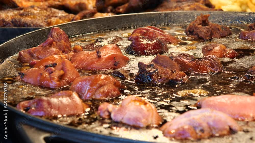 Tasty hot juicy steaming fat pieces of meat being deep fried, fatty food cooking, preparing, street food festival market stall detail, closeup, nobody, slow motion. Unhealthy fats, cholesterol concept Tasty hot juicy steaming fat pieces of meat being deep fried, fatty food cooking, preparing, street food festival market stall detail, closeup, nobody, slow motion. Unhealthy fats, cholesterol concept