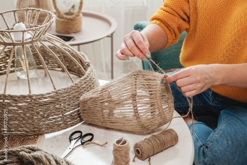 Fotografie Close up Woman makes handmade diy lamp from jute rope
