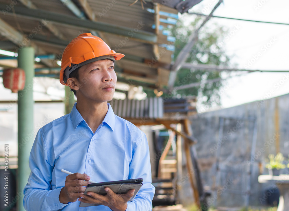 Young Asian foreman taking notes on his tablet, Business concept and technology. Young Asian foreman taking notes on his tablet, Business concept and technology.