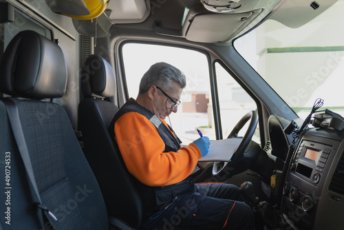 middle-aged paramedic with white hair writing on a paper in an ambulance. stock photography