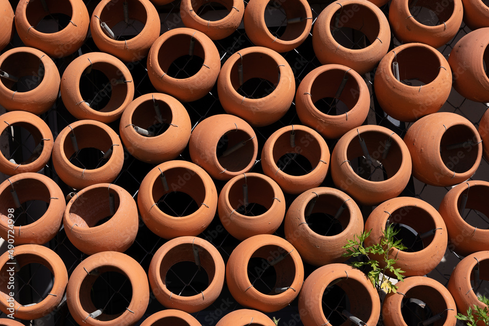 many clay pots stacked together form a beautiful patterned wall. many clay pots stacked together form a beautiful patterned wall.