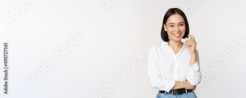 Young asian woman, professional entrepreneur standing in office clothing, smiling and looking confident, white background photo