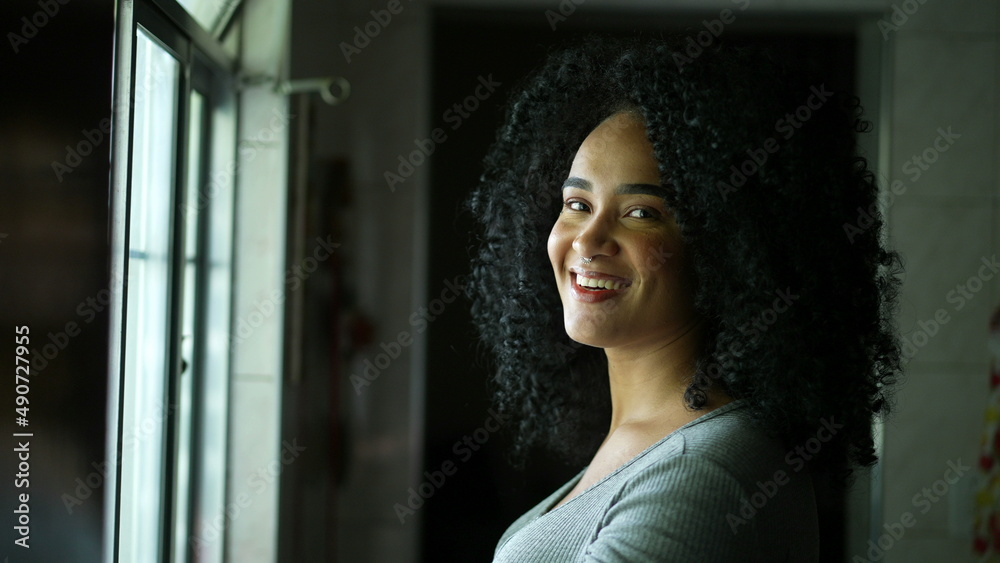 A young Brazilian woman turning head to camera smiling a diverse person portrait