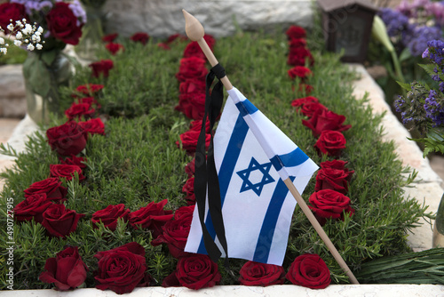 A flag of the State of Israel rests on a grave of a fallen soldier covered with colorful flowers in the Har Herzl military cemetery in Jerusalem on Memorial Day in Israel.
