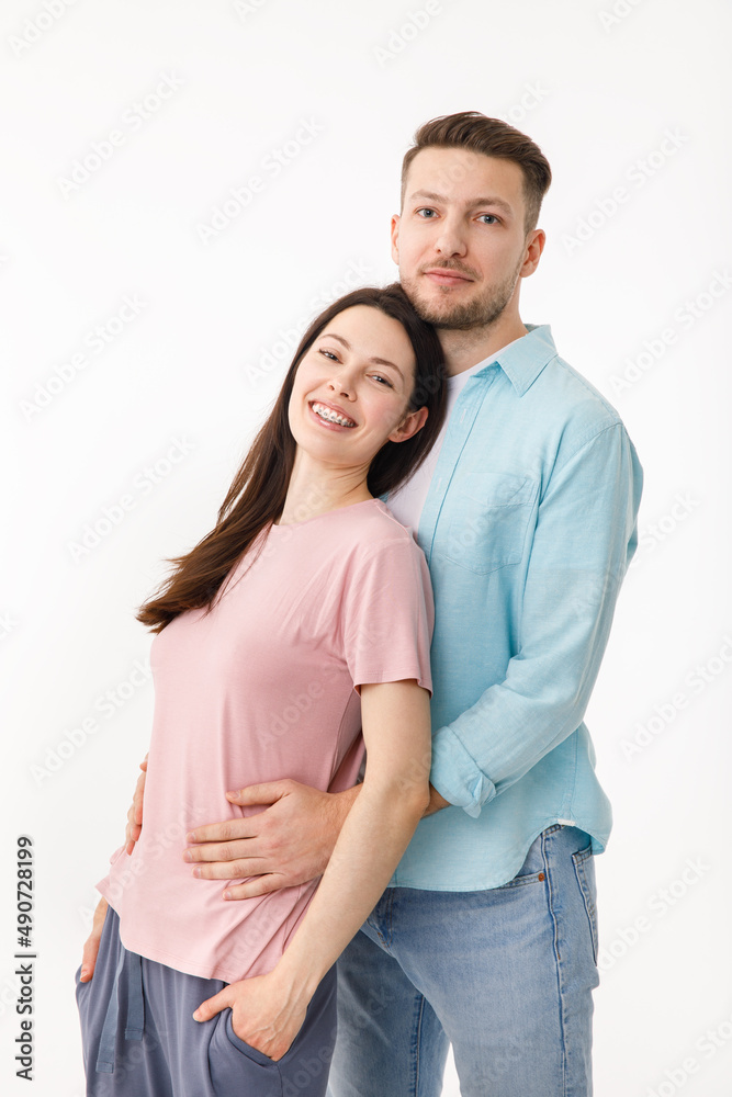 Portrait of a beautiful beloved couple. A guy and a girl hug each other and look at the camera smiling . On a white background Portrait of a beautiful beloved couple. A guy and a girl hug each other and look at the camera smiling . On a white background