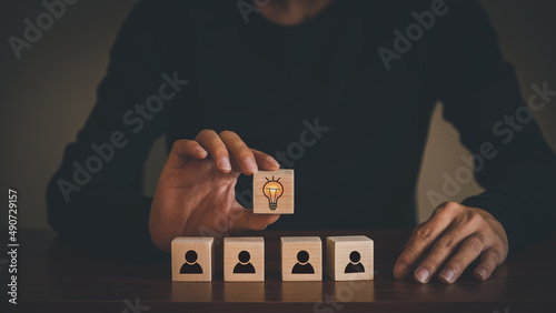 business ideas of creativity and innovation Hand picked wooden cube block with light bulb icon (new concept) above wooden block with colleague symbol icon representing teamwork.