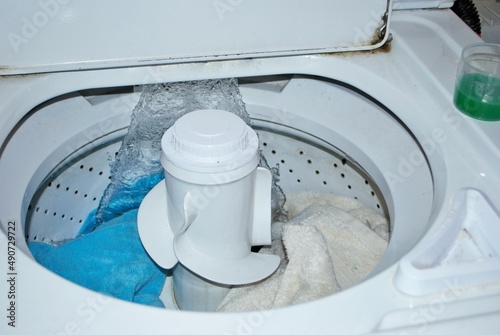 load of dirty towels in a washing machine filling with water