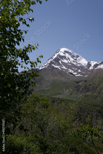 The mountain ranges of Georgia, Kazbegi, where two mountains form a triangular shape and above them a mountain spice that is covered with white snow