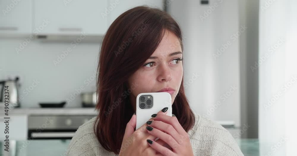 Relaxing. Happy woman watching videos, typing message on mobile phone sitting on a couch Relaxing. Happy woman watching videos, typing message on mobile phone sitting on a couch