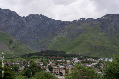 view of the mountain village from a high hill where you can see the green mountains and brown roofs around the village