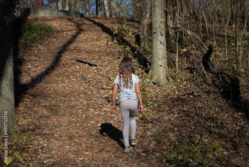 unrecognizable little girl hiking through the woods by herself