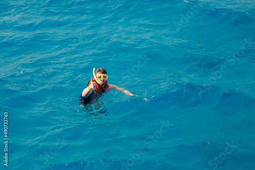Traveler man swimmer with mask and snorkel is engaged in snorkeling in red sea  turquoise clear water. Concept Travel Egypt Hawaii