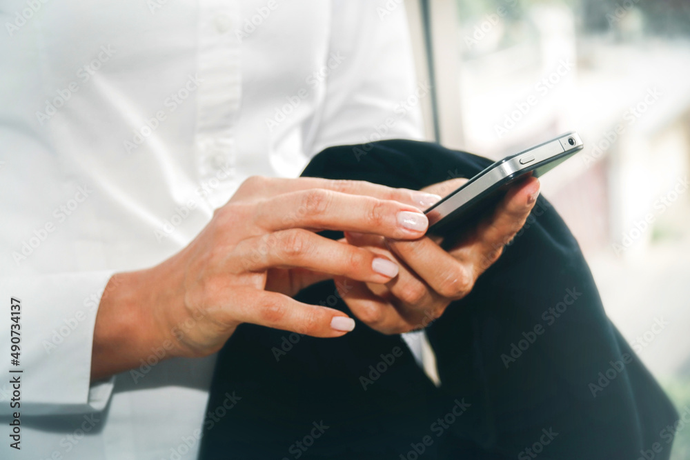 Hands of businesswoman searching for Internet messages on a modern touchscreen smartphone are part of everyday life while standing in the office. Hands of businesswoman searching for Internet messages on a modern touchscreen smartphone are part of everyday life while standing in the office.
