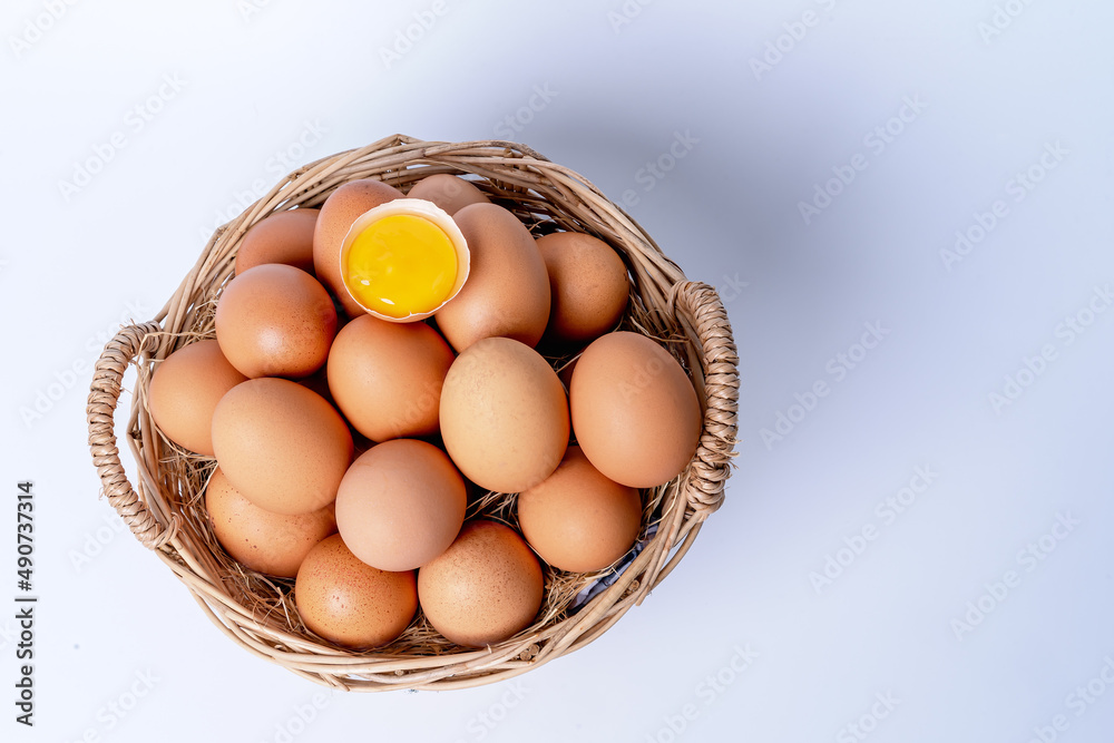 Fresh eggs collected inside wicker basket and one broken, suitable as a food ingredient. Fresh eggs from quality organic farms isolated on white background. Healthy food concept Fresh eggs collected inside wicker basket and one broken, suitable as a food ingredient. Fresh eggs from quality organic farms isolated on white background. Healthy food concept