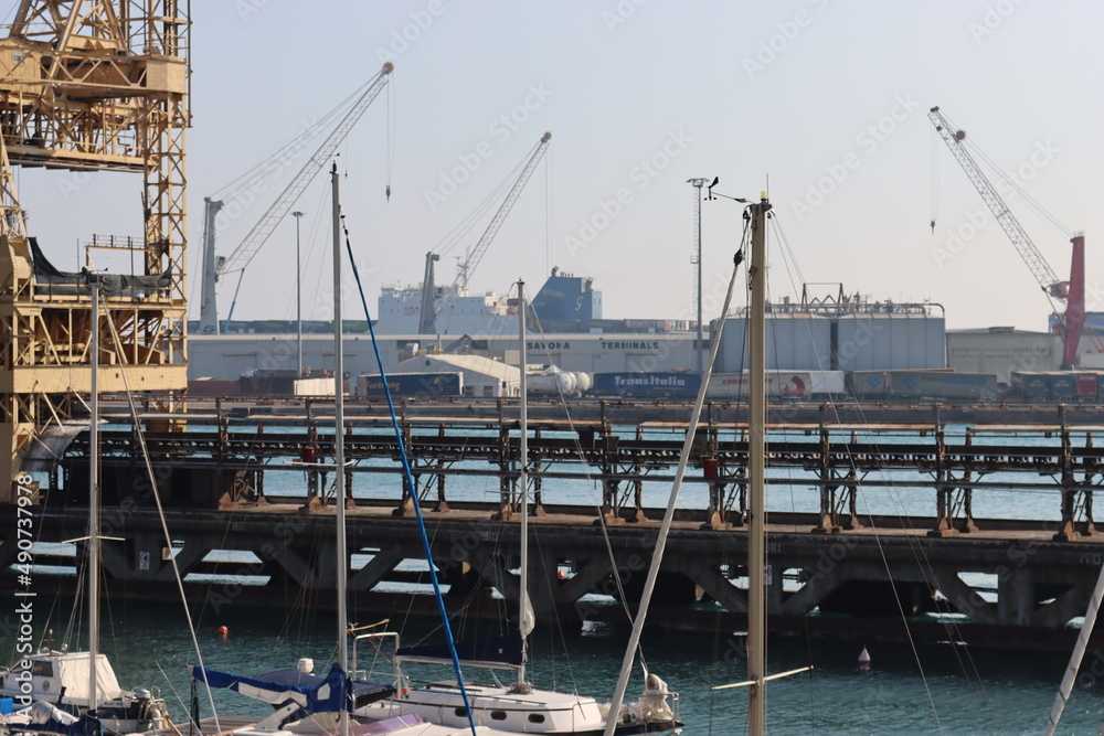 SAVONA, ITALY - February 12, 2022 - The port of Savona in the heart of the city on the italian riviera. Some old  container lifter near the new area. Beautiful small boats parked.