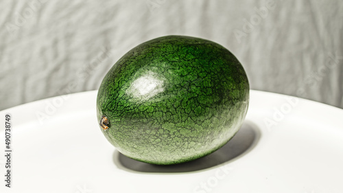 Obraz na płótnie Small, fresh, dark green watermelon of the Dragon's Egg variety on a white-grey background w salonie