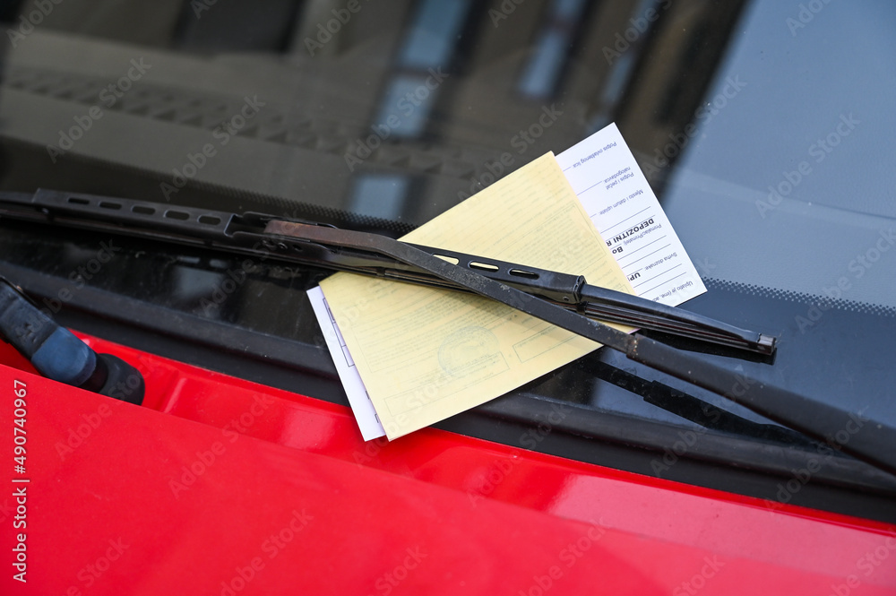 Car with penalty charge notices on the street. Ticket fine on windscreen for parking violation. Parking notice enclosed. - obrazy, fototapety, plakaty 