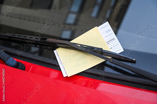 Fototapeta Naklejka Na Ścianę i Meble -  Car with penalty charge notices on the street. Ticket fine on windscreen for parking violation. Parking notice enclosed.