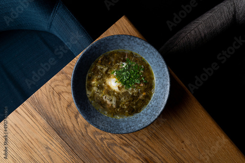 Fresh sorrel soup on a wooden table of a dark restaurant