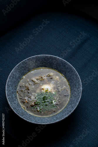 Spring eastern european soup with beef stock and fresh sorrel, black background