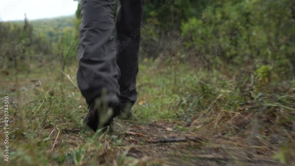 Man in trekking shoes walking. Hiker feet in forest. Close view a leg man walking with journey in the park in the forest. Travel Concept, Active People. Camera moving to hiker sneakers. Man in trekking shoes walking. Hiker feet in forest. Close view a leg man walking with journey in the park in the forest. Travel Concept, Active People. Camera moving to hiker sneakers.