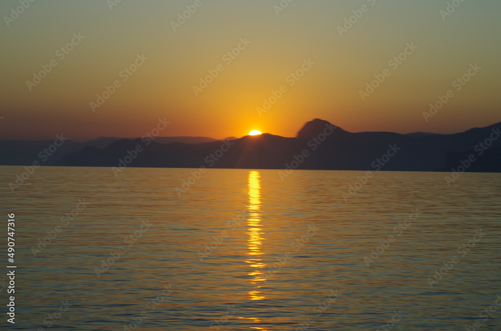 Peaceful sunset or sunrise on the seashore landscape in calm and quiet. Low sun, orange warm nighttime yellow light. Suitable for backgrounds and wallpapers. Soft focus