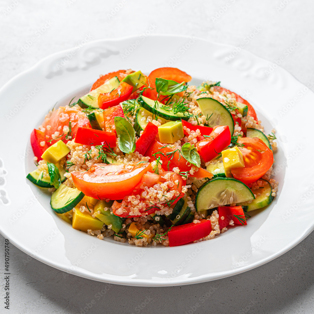 Healthy vegetable salad with quinoa and fresh herbs on a gray background.
