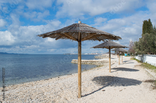 Fototapeta Naklejka Na Ścianę i Meble -  Pebble beach with straw parasol in small town Bibinje close to Zadar in Croatia, concept of relaxing vacation