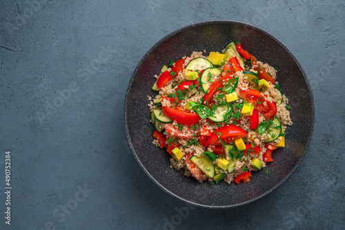 Salad with quinoa, avocado, tomato, cucumber and sweet pepper on a graphite background.