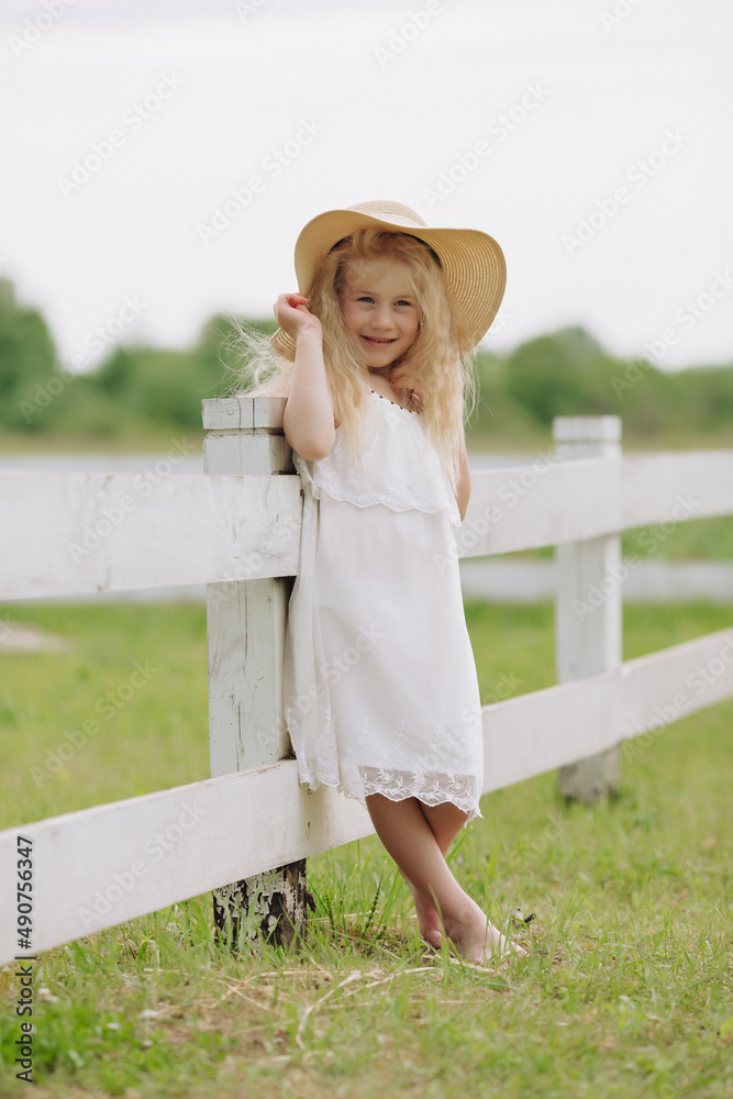 Beautiful and smart Ukrainian 7 year old girl near the white American fence on the ranch.