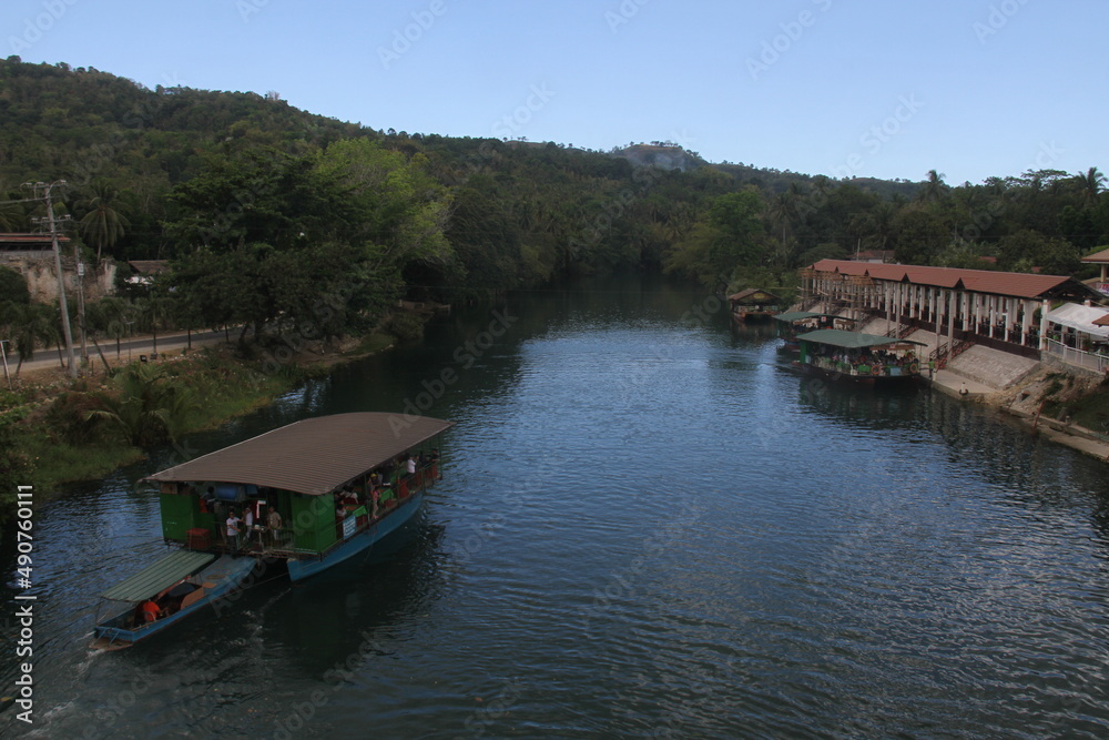 Aerial view of pier and tourist boat cruises through the Loboc green river in Loboc, Bohol, Philippines.