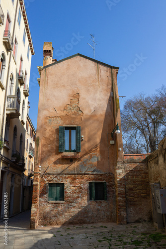 Glimpse of Venice. Detail of a small red brick building and peeling plaster. Vertical image.