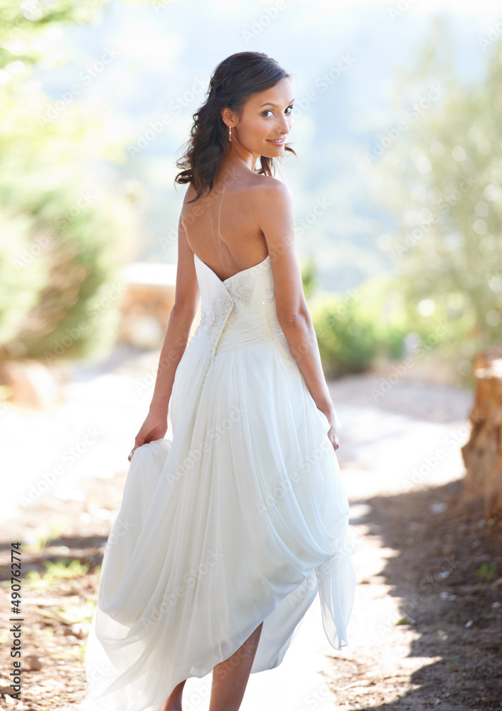 Walking towards her new husband. Portrait of an attractive young woman in a wedding dress looking back. Walking towards her new husband. Portrait of an attractive young woman in a wedding dress looking back.