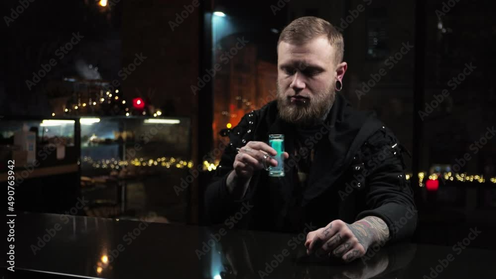 Bartender is a young man pours drinks, prepares alcoholic shots Medusa in the bar Serving the guest a drink