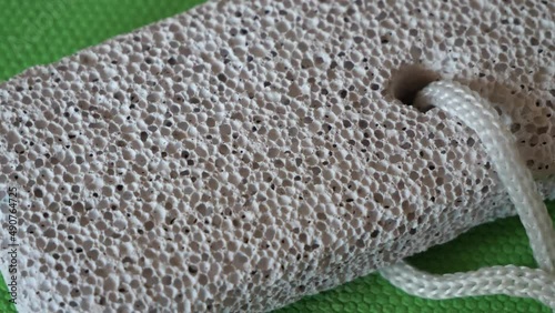 A block of pumice stone on a green surface, close-up.
