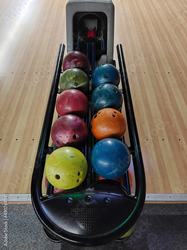 Bowling balls of different colors lie in two rows on a bowl stand